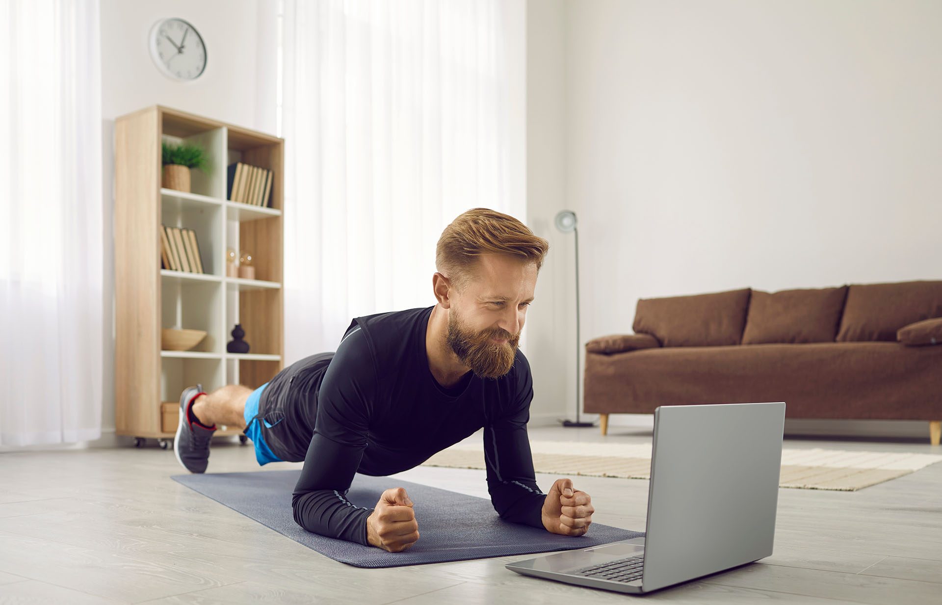 A man doing physical exercises at home while receiving guideance via video.