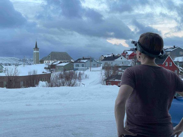 Dame med videobriller på ser ut over landsby i Norge.